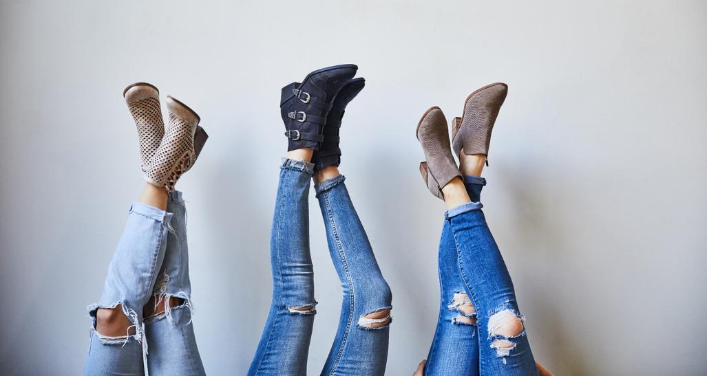 three women with their legs up show off their shoes from DSW