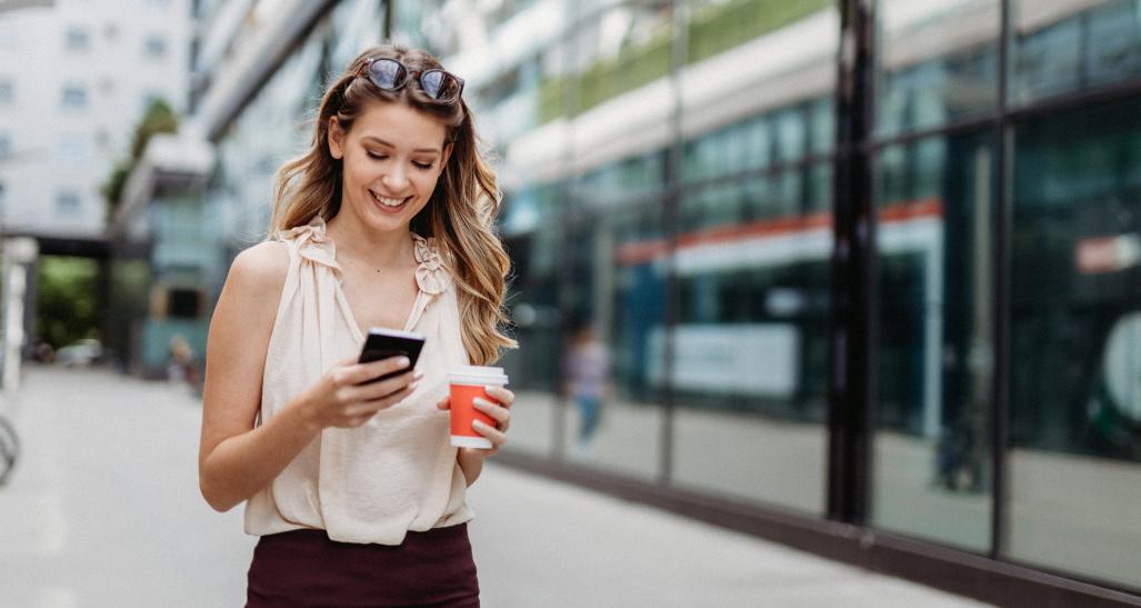 A woman looks at her phone on a city street