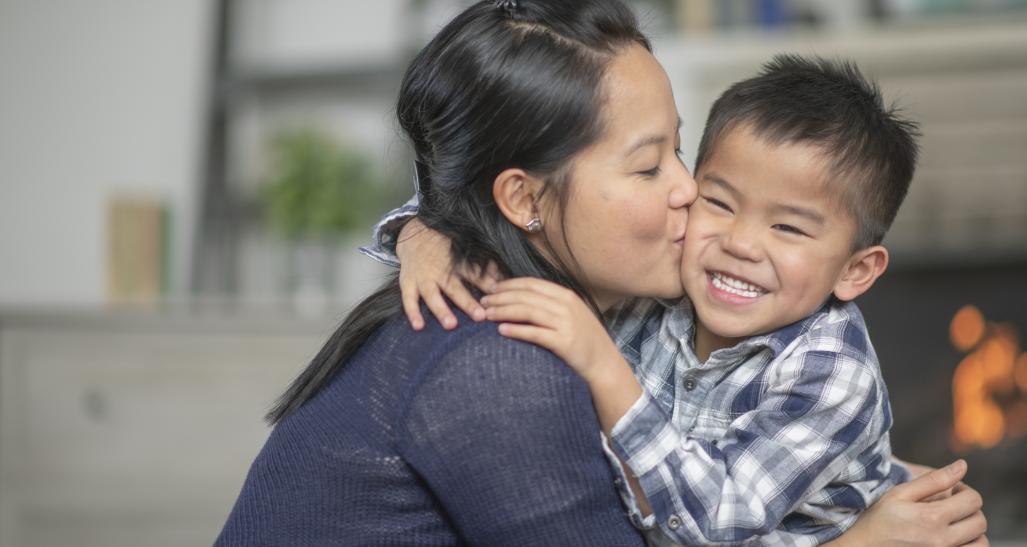 Mother kisses smiling young son