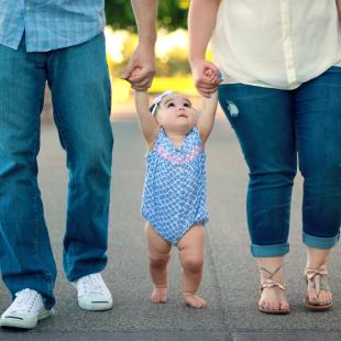 a mother and a father walking their toddler baby