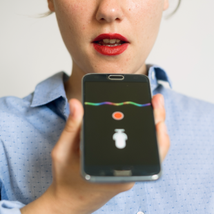 female speaking into her device's using voice assistance technology