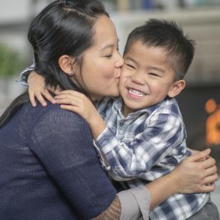 Mother kisses smiling young son