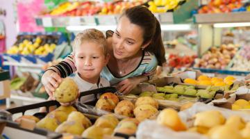 Mother and child shopping for groceries choosing fruit